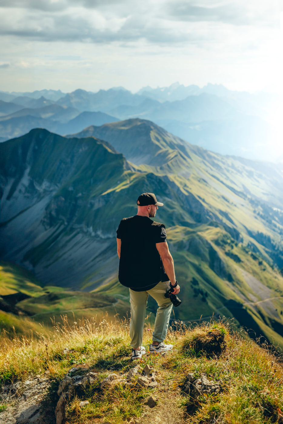 Max on a Swiss alpine ridge, camera in hand, looking over the peaks