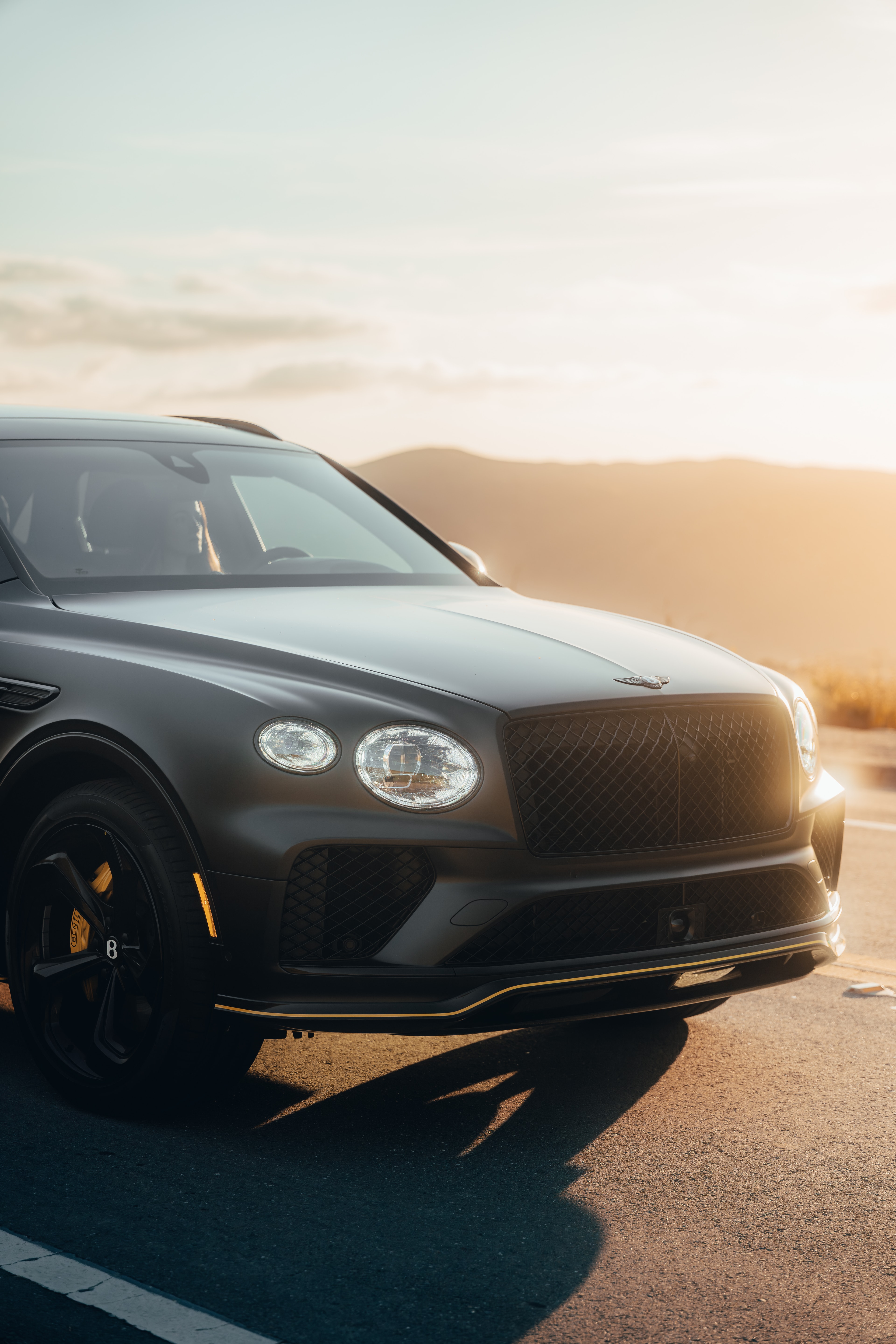 Bentayga front low-angle, dramatic golden hour lens flare