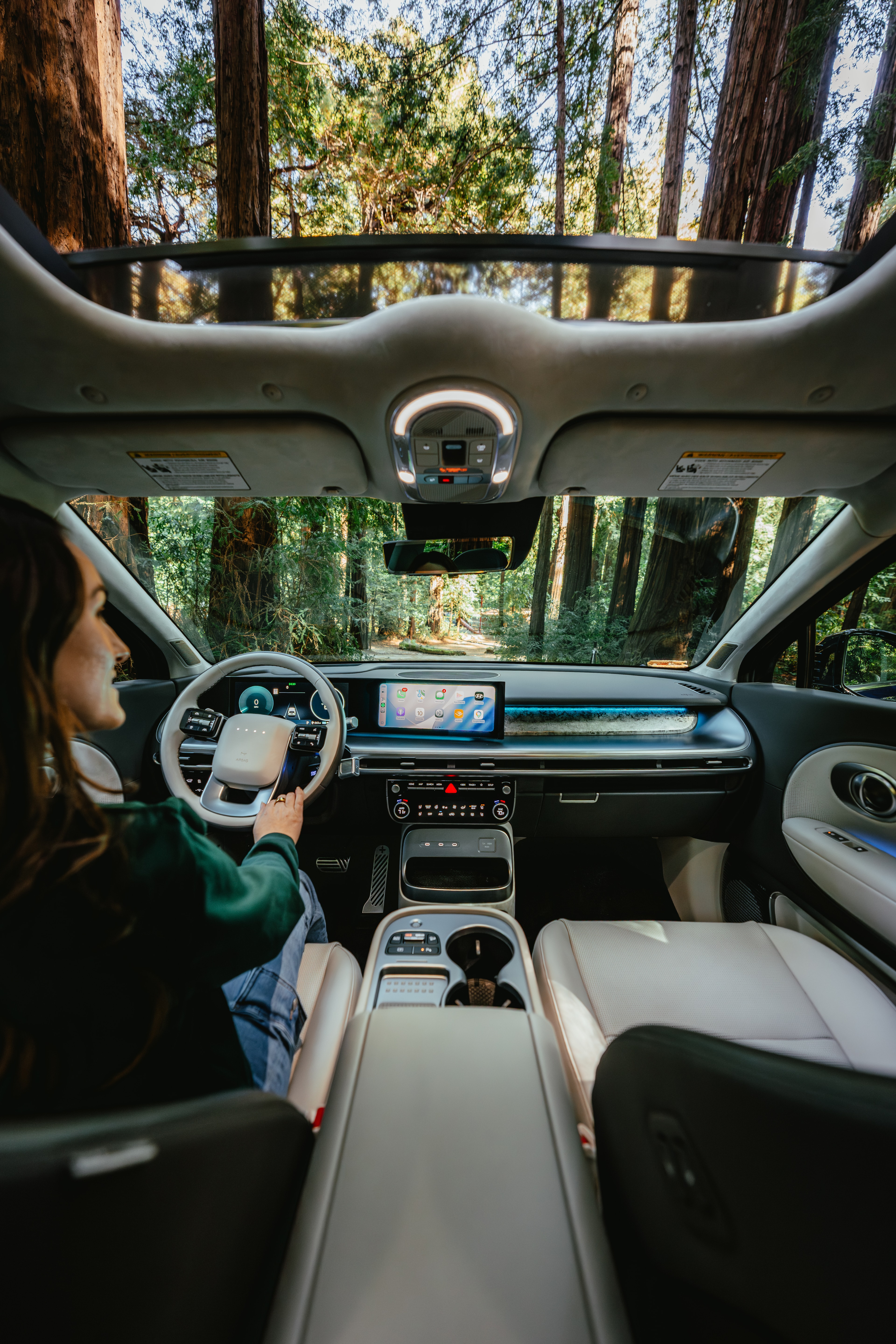 Interior of the IONIQ 9 with its glass roof, a forest road ahead