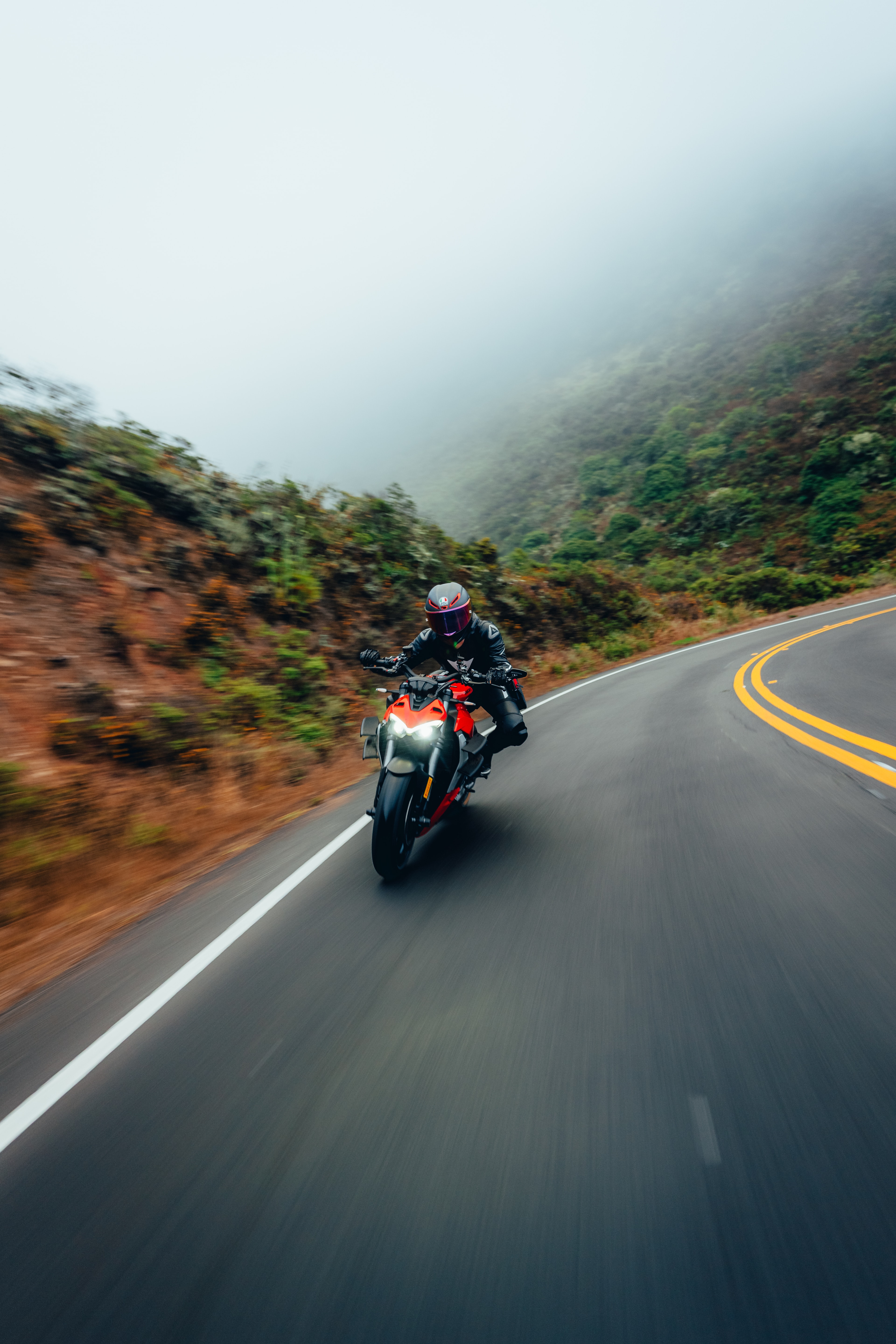 Single Panigale V4S rider on a foggy mountain road, headlight piercing the mist