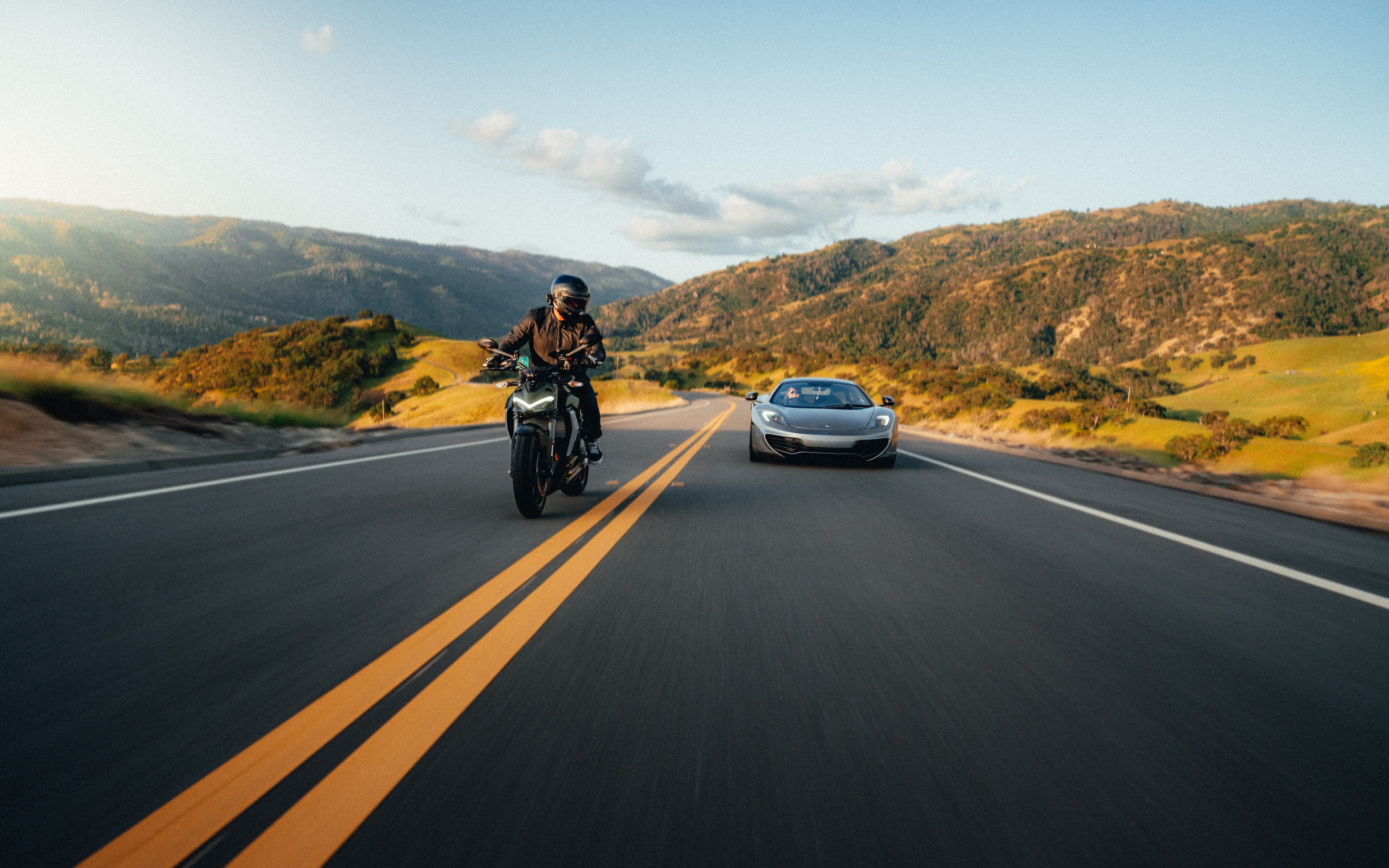 Ducati Street Fighter alongside a silver McLaren on a golden-hour Bay Area road