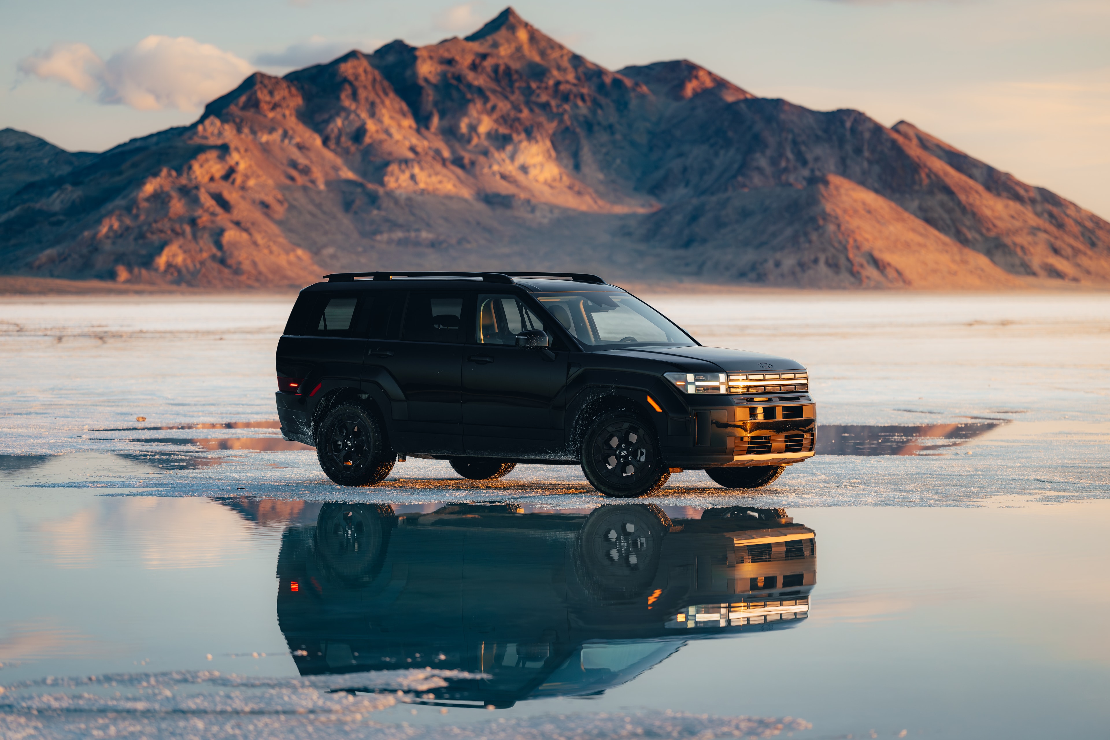 Hyundai Santa Fe side profile on the Bonneville salt flats, mountain reflection at golden hour
