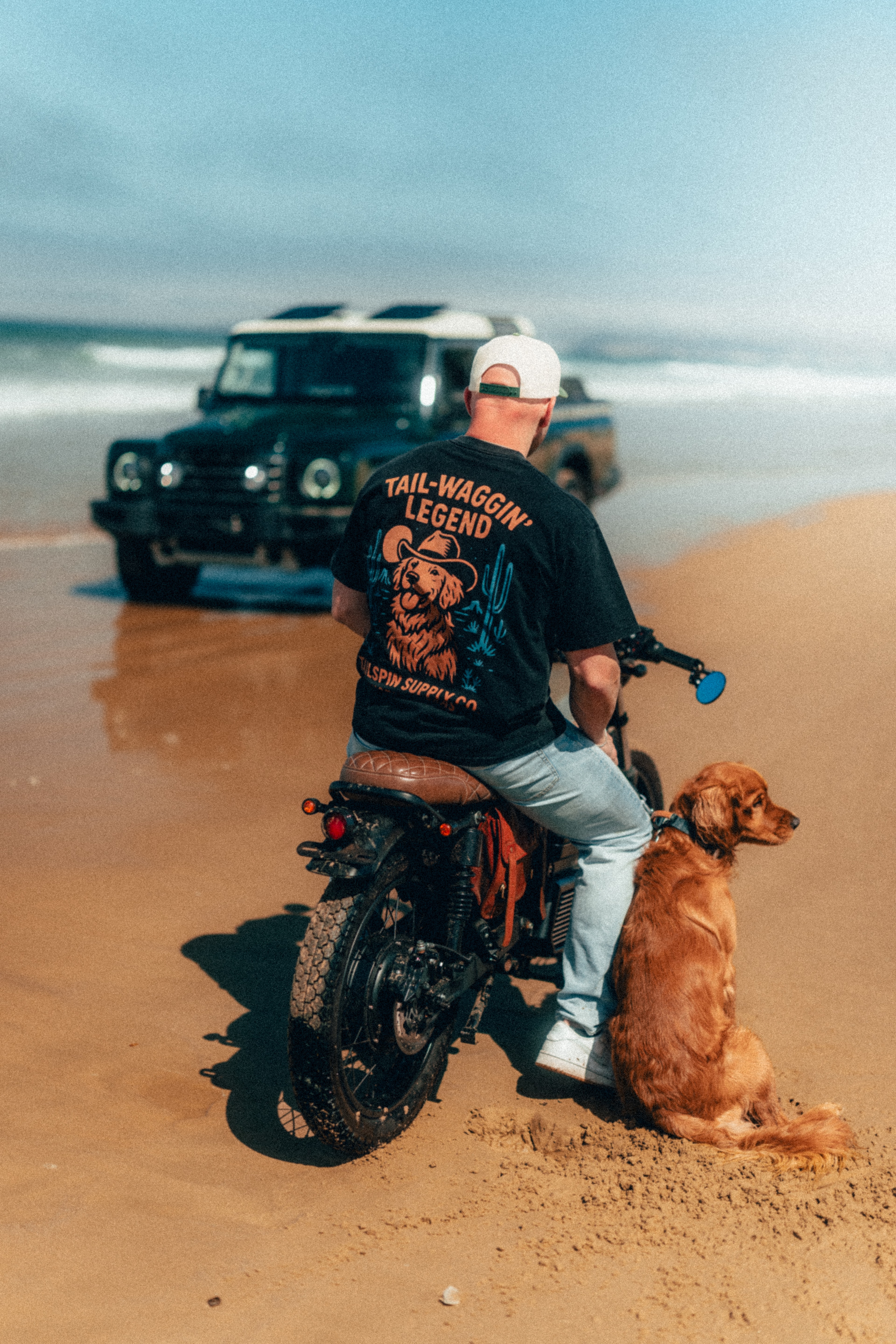 Rider from behind on the Beachman with a golden retriever, sunlit Pismo beach