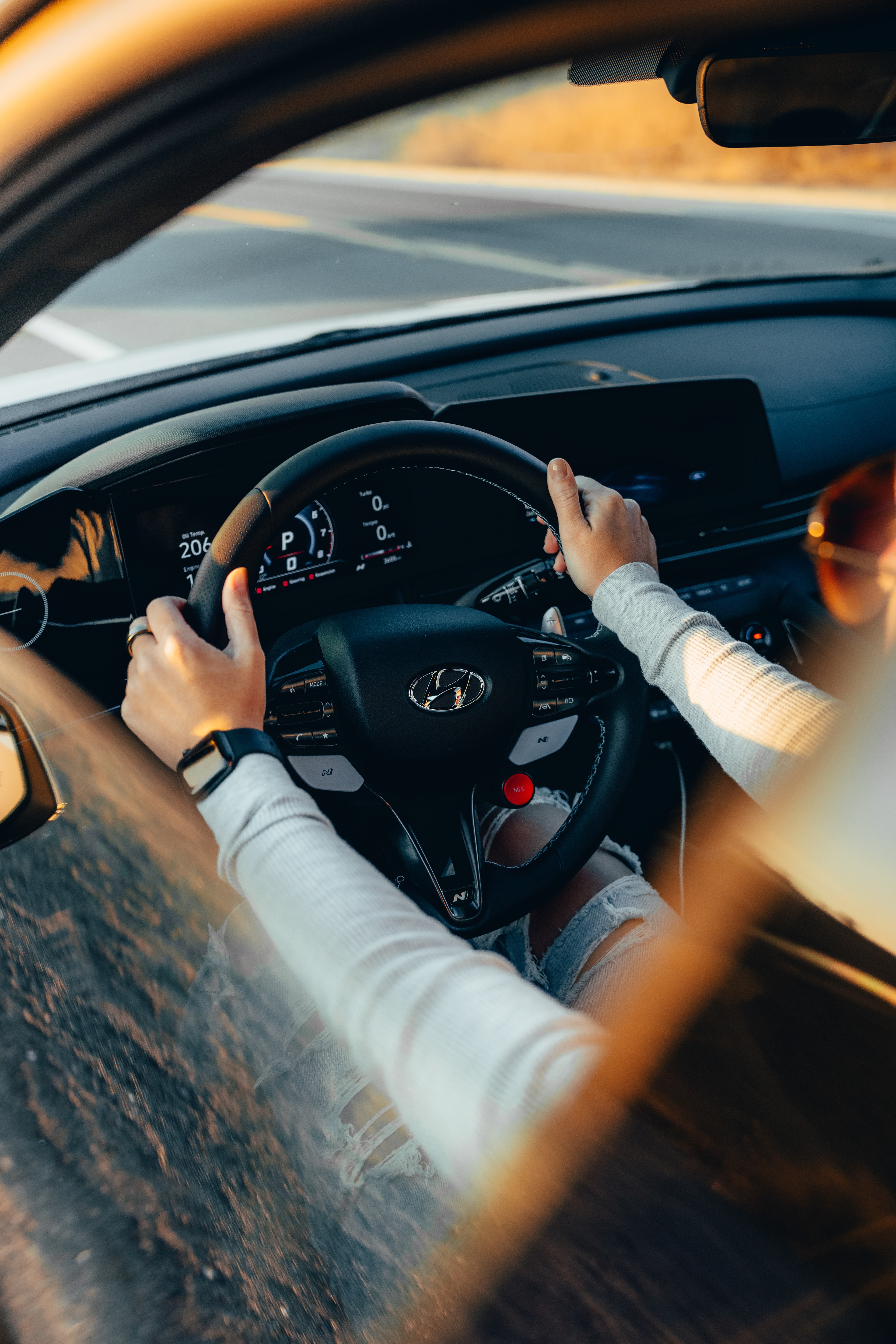 Hands on the Elantra N steering wheel, golden light through the window