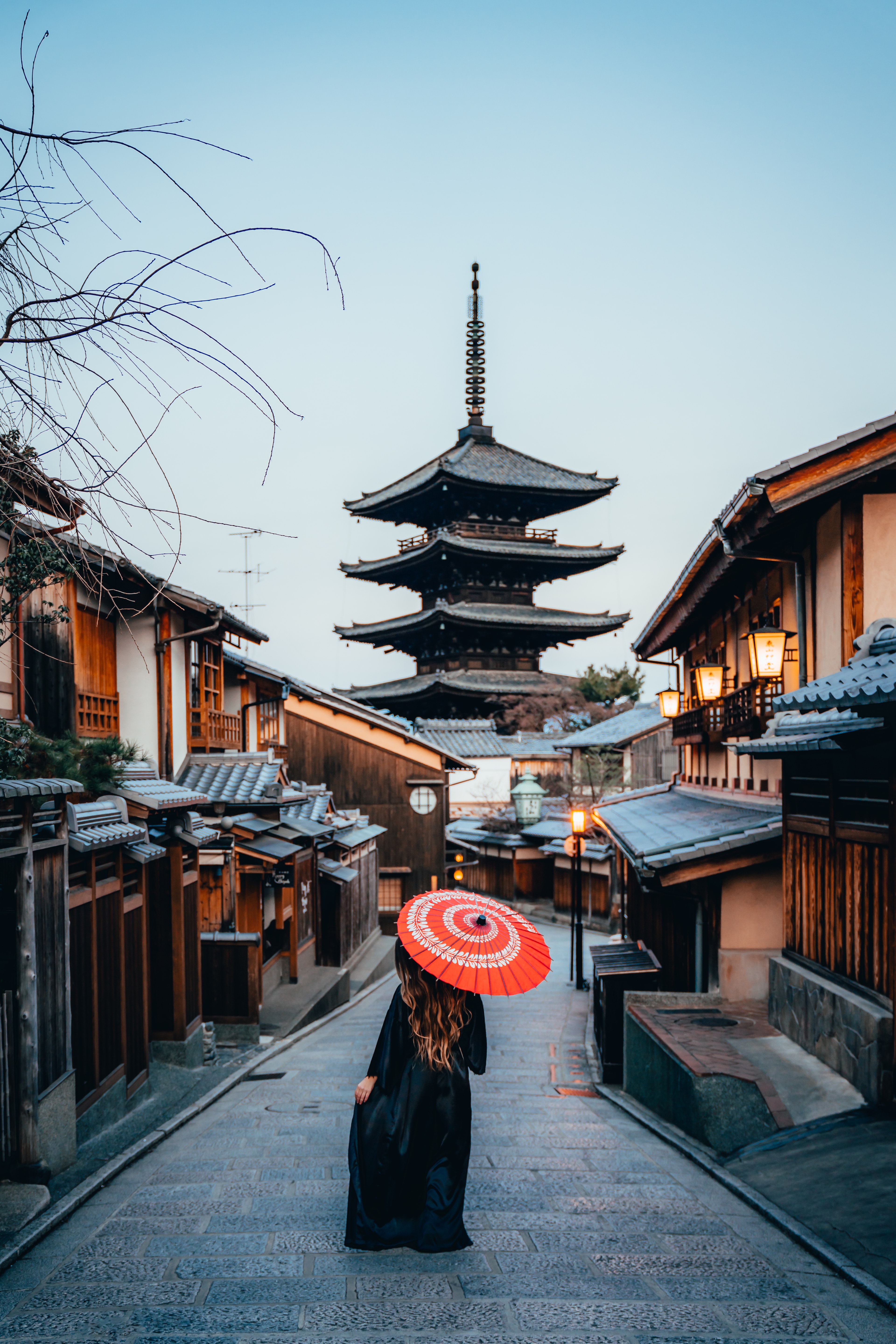 A woman with a red parasol on the Yasaka pagoda lane in Kyoto at first light